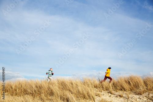 Girls playing on sand dunes under clouds photo