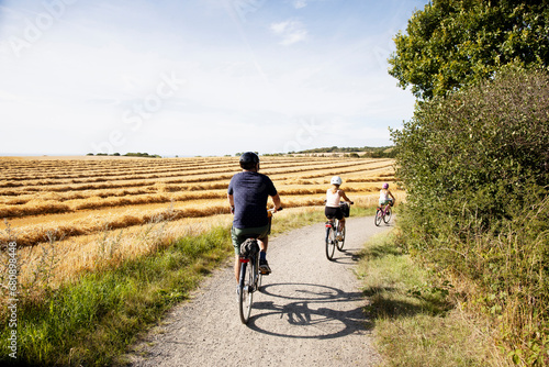 Man and his daughters bicycling on rural road photo