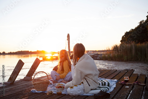 Sisters sitting on jetty at sunset photo