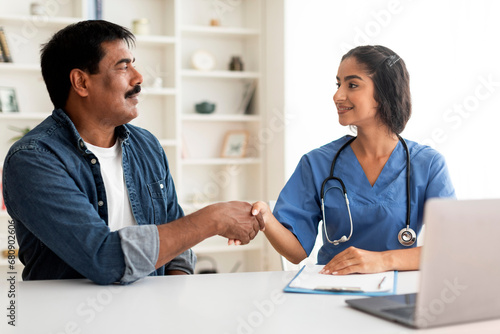 Medical Services. Indian Doctor Woman In Uniform Shaking Hands With Male Patient