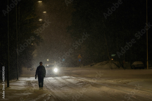 Man walking in snow on road photo