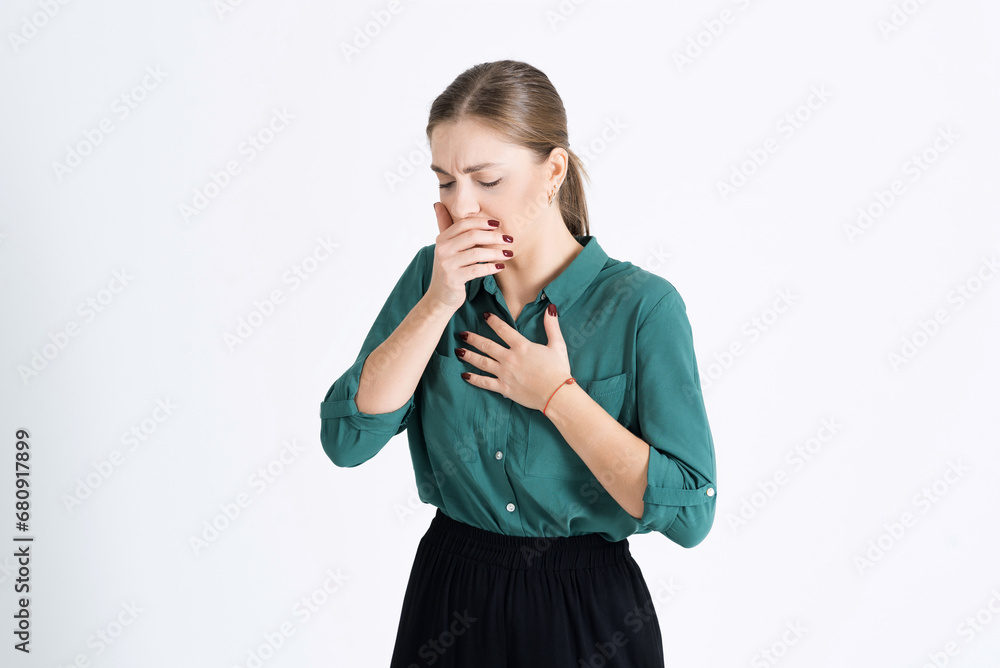 Attractive young woman touches her chest and coughs. Feels bad and sneezes. An unhealthy girl isolated on a white studio background. The concept of virus, flu and disease Attractive young woman touches her chest and coughs. Feels bad and sneezes. An unhealthy girl isolated on a white studio background. The concept of virus, flu and disease
