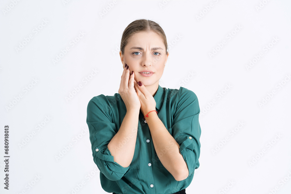 Attractive young woman shows a painful facial expression, touches her cheek because of a toothache isolated on a white studio background. The concept of health care and dental care. Attractive young woman shows a painful facial expression, touches her cheek because of a toothache isolated on a white studio background. The concept of health care and dental care.