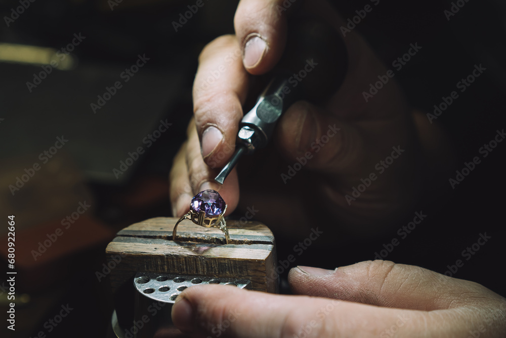 Close up of a goldsmith's hand making a gold or silver ring or a diamond using goldsmith's tools. For this work it takes precision and patience. Concept of: tradition, luxury, jewelry. - obrazy, fototapety, plakaty 