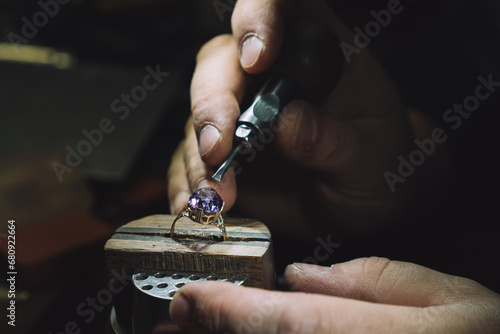 Close up of a goldsmith's hand making a gold or silver ring or a diamond using goldsmith's tools. For this work it takes precision and patience. Concept of: tradition, luxury, jewelry. photo