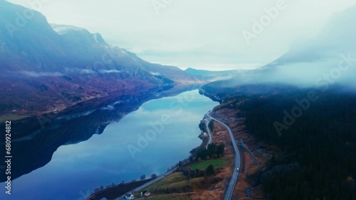 Breathtaking Drone Footage of Mountains, Fjord, and Waterfall with Lush Trees and Clouds Creating a Scenic Natural Landscape