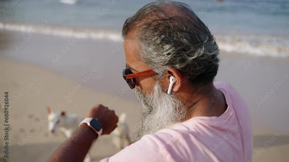 Senior man running in headphones at shore, checks fitness tracker watch activity, pace, calories, distance. Black old male jogging at beach, active lifestyle on retirement. Mature person doing sport. Senior man running in headphones at shore, checks fitness tracker watch activity, pace, calories, distance. Black old male jogging at beach, active lifestyle on retirement. Mature person doing sport.