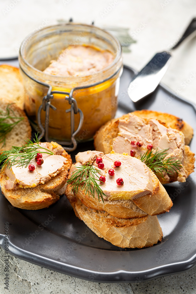 Bread or baguette toast with foie gras pate, a specialty food product made of the liver of a duck or goose, in a glass jar. Popular and well-known delicacy in French cuisine. Vertical image. Bread or baguette toast with foie gras pate, a specialty food product made of the liver of a duck or goose, in a glass jar. Popular and well-known delicacy in French cuisine. Vertical image.