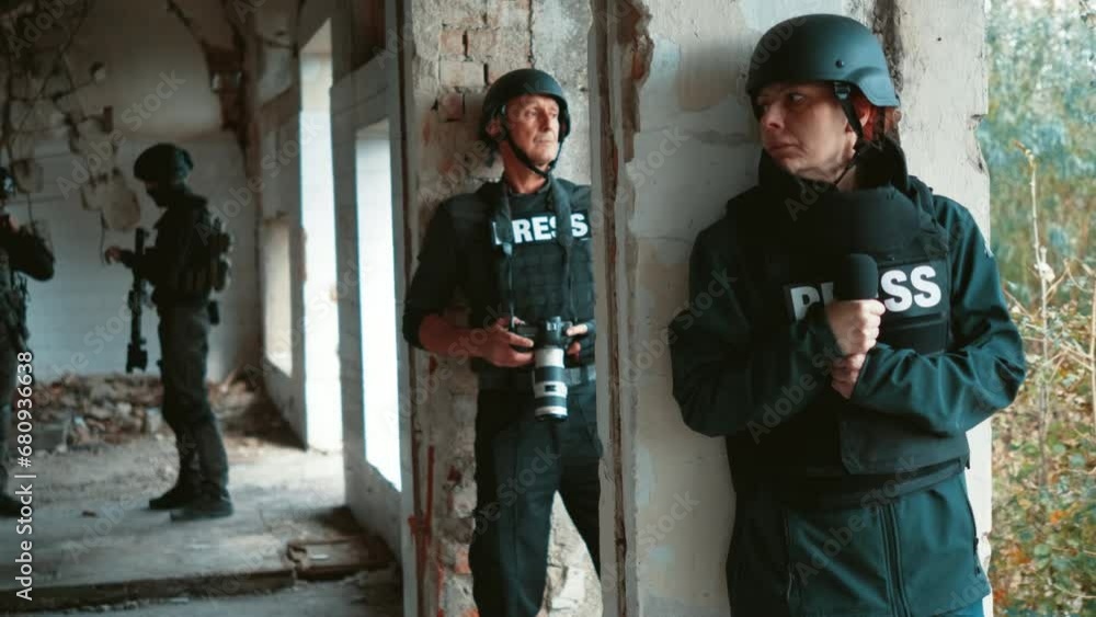 War correspondents, journalists hide behind a wall from soldiers in a war zone War correspondents, journalists hide behind a wall from soldiers in a war zone