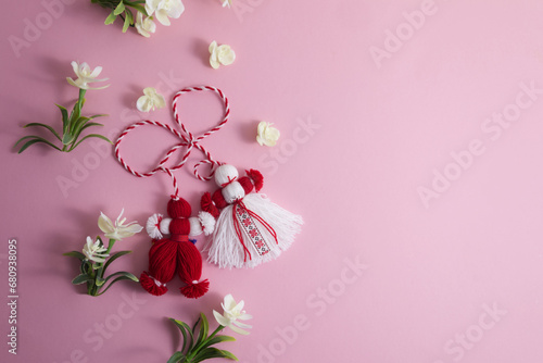 Martenitsa, Martisor among spring flowers on a pink background flat lay copy space photo