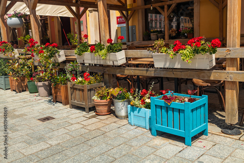 Town flowers in the big wooden pots on street. Interior street cafe with flowers in wooden pot. High quality photo