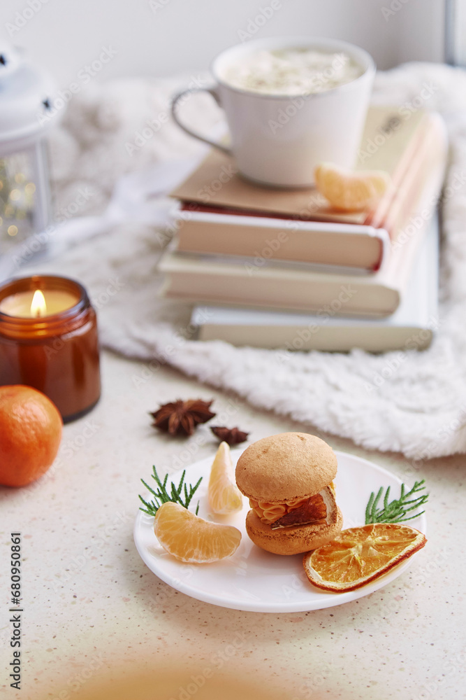 Aesthetics dessert bright orange macaroon, tangerines among books, candle and coffee. Festive table setting Aesthetics dessert bright orange macaroon, tangerines among books, candle and coffee. Festive table setting
