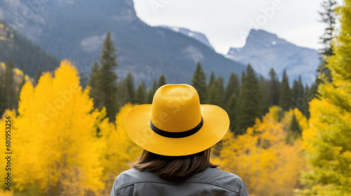 Blonde cowgirl in hat at meadow with mountains on background photo