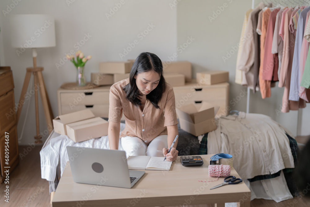 Busy Asian woman preparing package delivery box Shipping for shopping online taking note of order with laptop young start up small business owner online shop Busy Asian woman preparing package delivery box Shipping for shopping online taking note of order with laptop young start up small business owner online shop