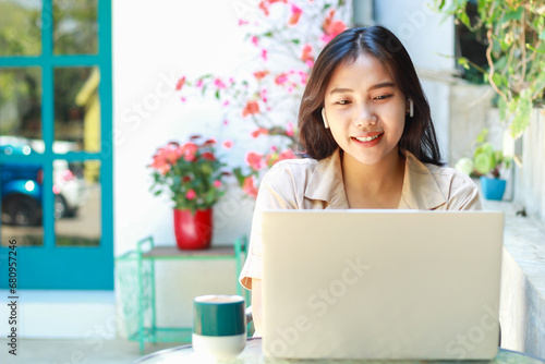 happy asian woman sitting in cafe working on laptop with smile wearing fashionable casual clothes, female small business owner in outdoors