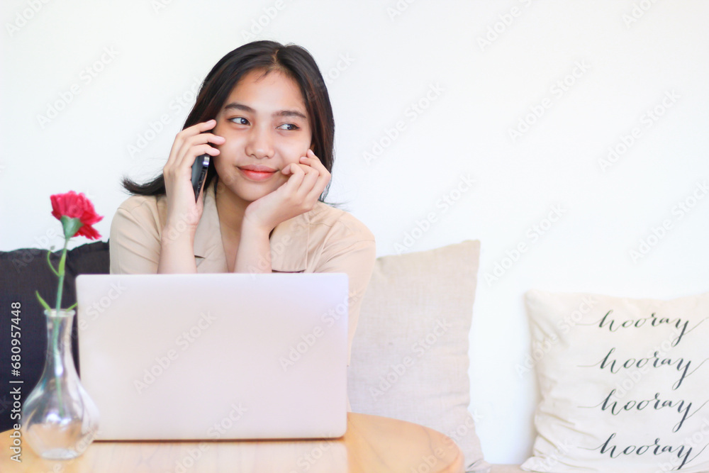 happy asian woman sitting on sofa answer call on smartphone and working with laptop wearing casual clothes, female designer working on project at home happy asian woman sitting on sofa answer call on smartphone and working with laptop wearing casual clothes, female designer working on project at home