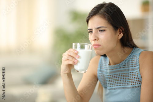 Disgusted woman smelling expired milk photo