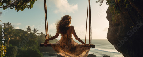 Woman swinging in sunset light. Rear view of girl swing against forest background. © Alena