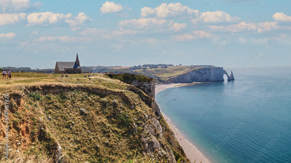 Aerial panoramic view of Etretat coastline with white chalk cliffs, natural stone arch and the beach. Etretat, Normandy, France.