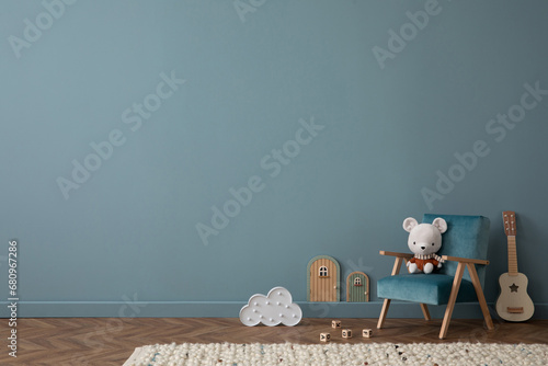 Cozy composition of blue living room interior with copy space, gray desk, green chair, plush dog, braided rug, colorful garland on wall, wooden wall, and personal accessories. Home decor. Template. photo