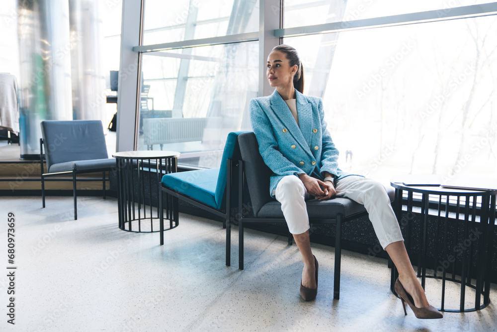 Stylish woman sitting on armless chair while resting in cafe