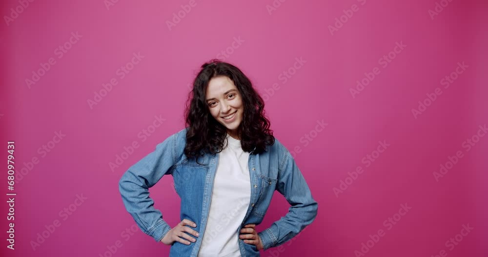 Static shot of cheerful young female with black hair clenching fists and looking at camera with smile while celebrating success against pink background. show the like sign. Static shot of cheerful young female with black hair clenching fists and looking at camera with smile while celebrating success against pink background. show the like sign.