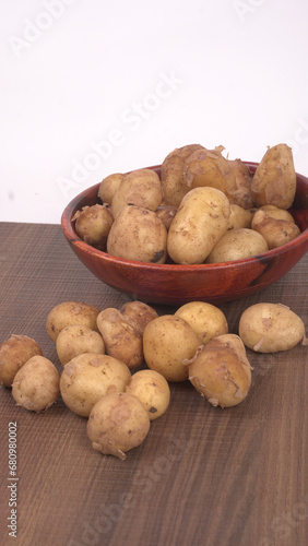 Fresh small potatoes for cooking in a wooden bowl. With copy space on white background.