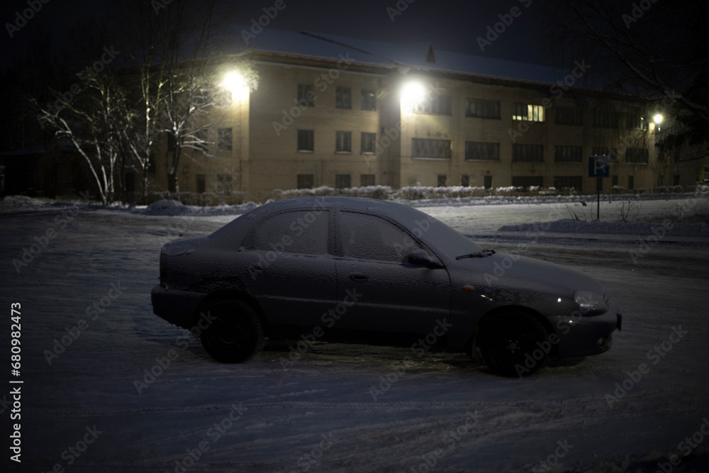 Car in parking lot in winter at night. Transport in snow in dark.