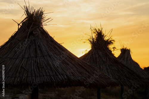 Sunset over thatched beach umbrellas