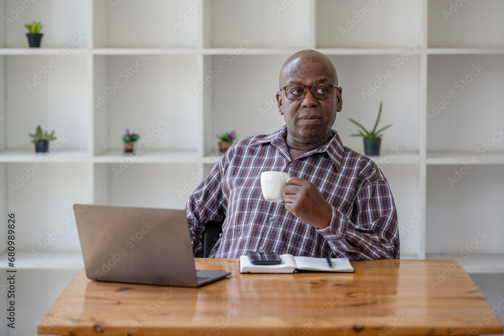 Senior black man taking a coffee break while working on a laptop. Senior black man taking a coffee break while working on a laptop.