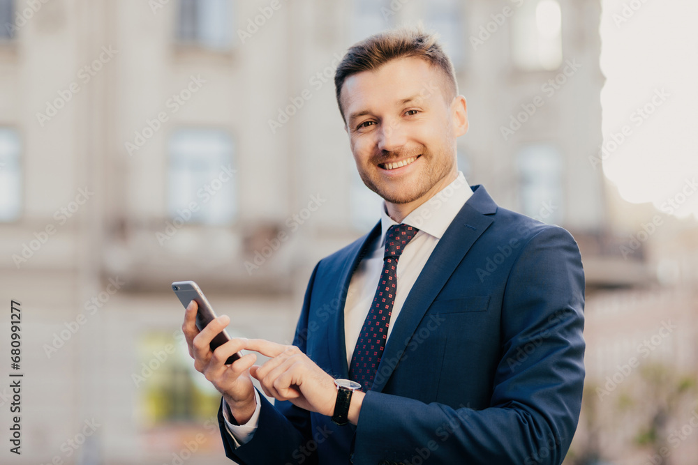 Joyful businessman checking his smartphone and smartwatch in an urban setting with historic architecture Joyful businessman checking his smartphone and smartwatch in an urban setting with historic architecture
