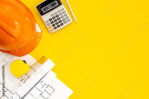 Top view of construction helmet on drawing blueprints for house designing and architect plan
