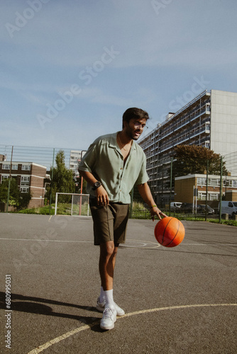 Canvas Print Young guy in stylish outfit playing basketball on urban court