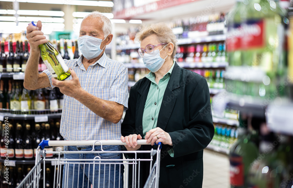 Φωτογραφία Mature european spouses chooses bottle of wine in alcohol section of supermarket