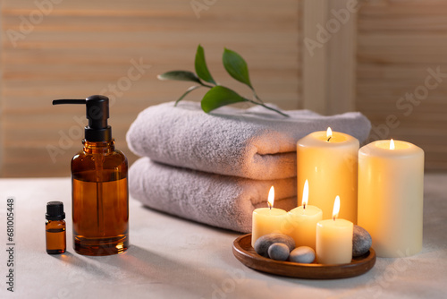Beauty spa treatment items on white wooden table. Candles, stones, essential oils and towels. Cosy bath.