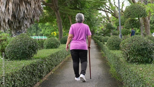 An old elderly Asian woman uses a walker and walking in the backyard in hospital. Physical therapy, Rehabilitation and senior health insurance concept. Medical for senior care osteoarthritis.