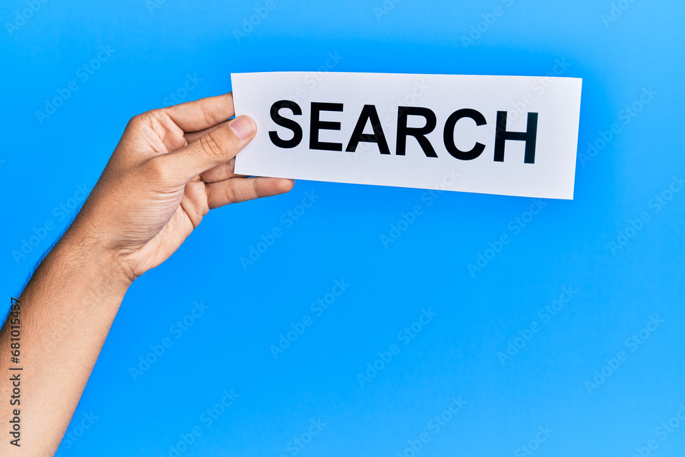 Hand of caucasian man holding paper with search word over isolated blue background Hand of caucasian man holding paper with search word over isolated blue background
