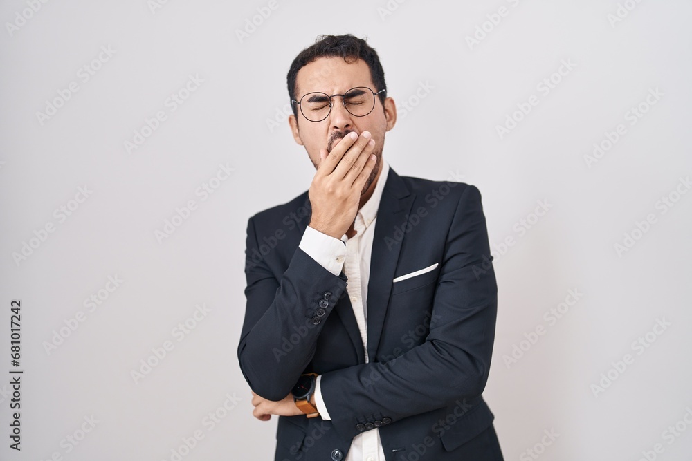 Handsome business hispanic man standing over white background bored yawning tired covering mouth with hand. restless and sleepiness. Handsome business hispanic man standing over white background bored yawning tired covering mouth with hand. restless and sleepiness.