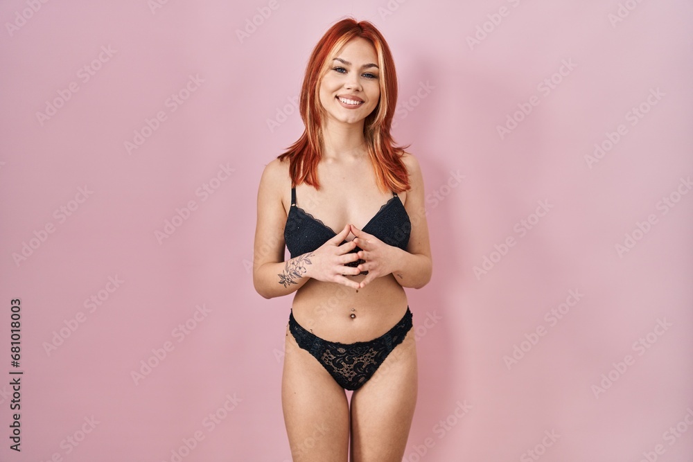Obraz premium Young caucasian woman wearing lingerie over pink background hands together and fingers crossed smiling relaxed and cheerful. success and optimistic