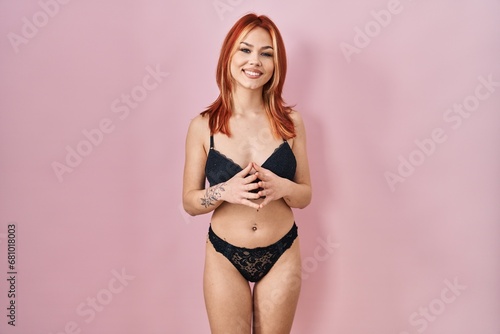 Young caucasian woman wearing lingerie over pink background hands together and fingers crossed smiling relaxed and cheerful. success and optimistic