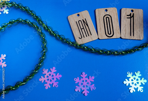 Festive blue background with text January 1st. Tinsel and snowflakes in the photo. New Year's mood concept. Winter holidays.