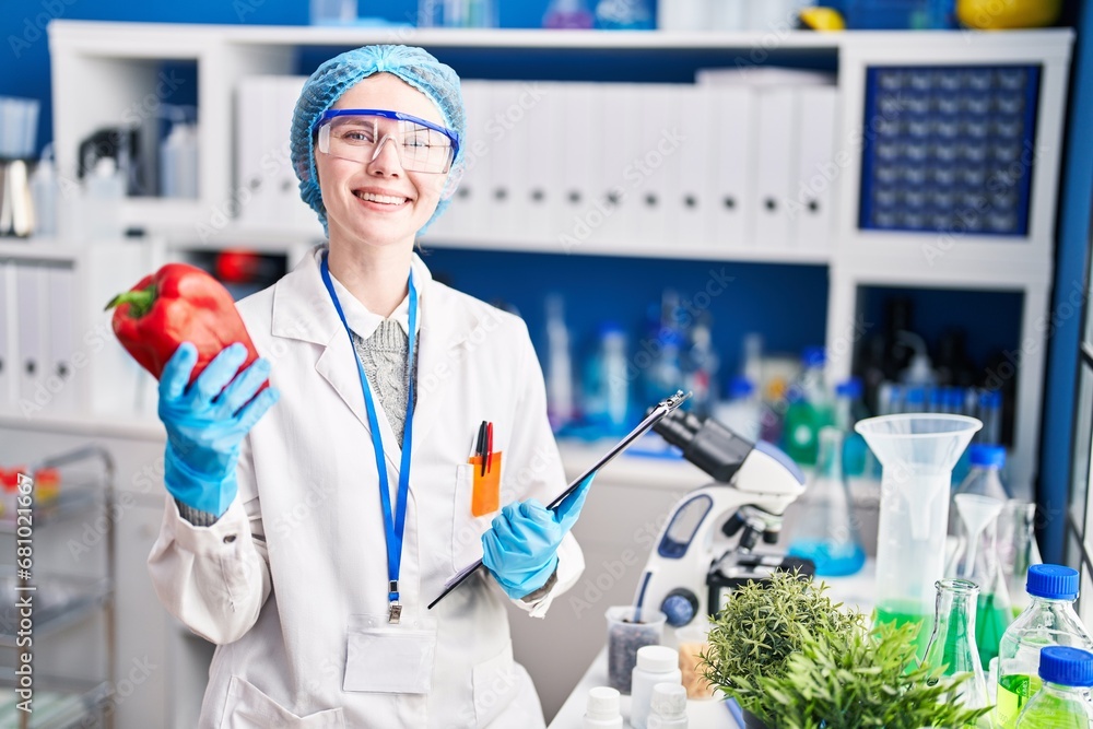 Young blonde woman scientist holding pepper and checklist at laboratory