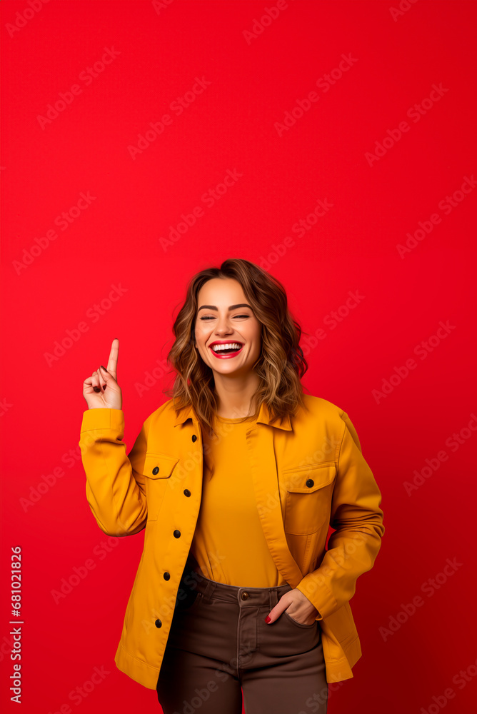 Smiling woman in yellow jacket pointing up, against red background.
