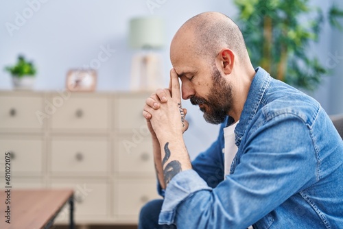 Young bald man stressed sitting on sofa at home