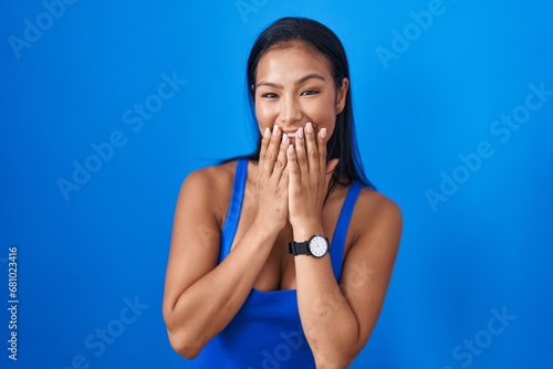 Schilderij op canvas Hispanic woman standing over blue background laughing and embarrassed giggle cov