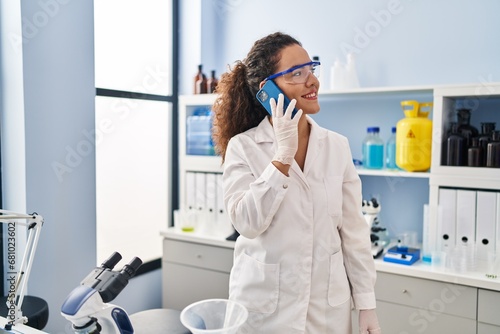 Young beautiful hispanic woman scientist talking on smartphone at laboratory