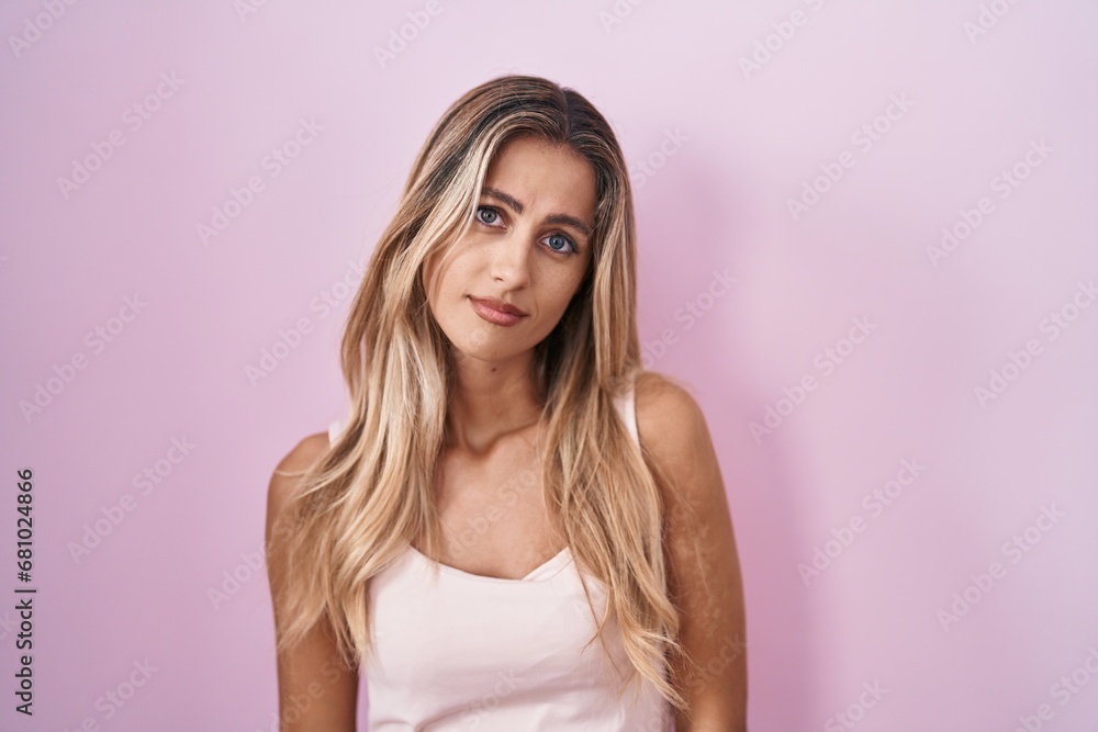 Young blonde woman standing over pink background looking sleepy and tired, exhausted for fatigue and hangover, lazy eyes in the morning. Young blonde woman standing over pink background looking sleepy and tired, exhausted for fatigue and hangover, lazy eyes in the morning.