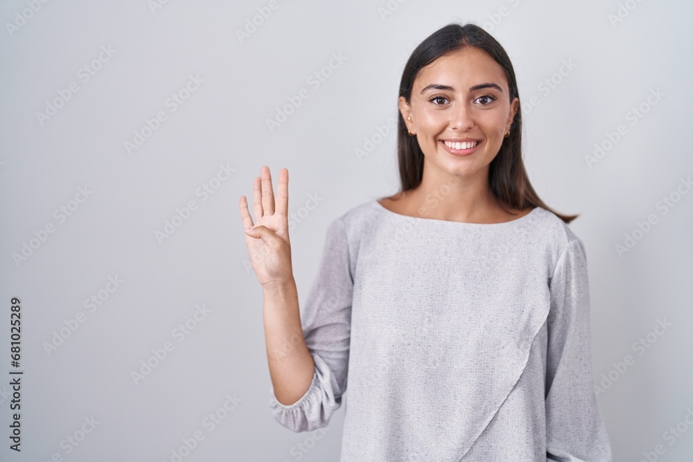 Young hispanic woman standing over white background showing and pointing up with fingers number four while smiling confident and happy. Young hispanic woman standing over white background showing and pointing up with fingers number four while smiling confident and happy.