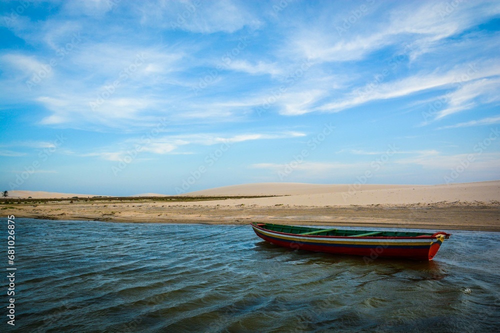 barco de pesca em uma lagoa no litoral nordestino brasileiro, com céu azul e dunas de areia ao fundo barco de pesca em uma lagoa no litoral nordestino brasileiro, com céu azul e dunas de areia ao fundo