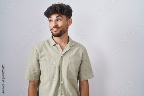 Arab man with beard standing over white background smiling looking to the side and staring away thinking.